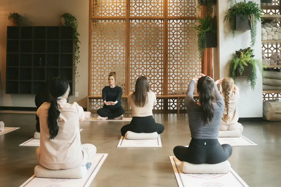 Una clase de yoga en el Sun Studio: quien guía se sienta al frente, ante personas sentadas sobre tapetes y bolsters.