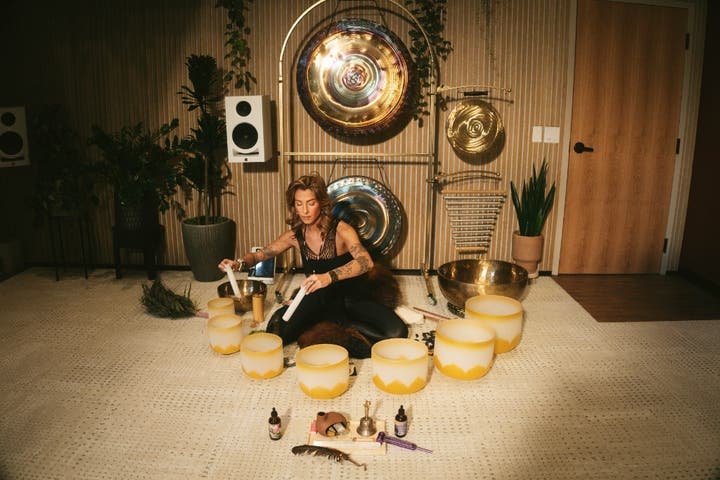 Practicante de baño de sonido sentada con cuencos de cristal y gongs en Sacred Society